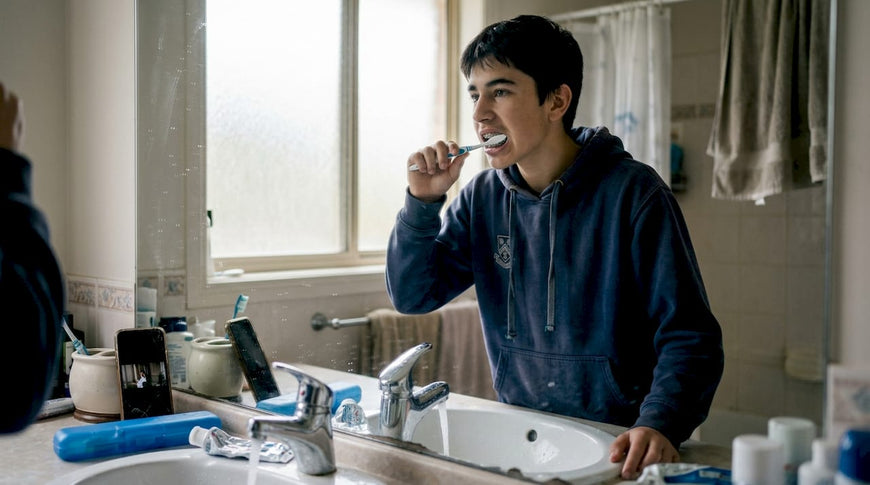Teen boy brushing teeth with braces in bathroom