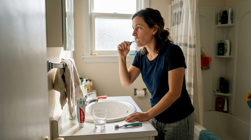 Woman brushing teeth at sunlit family bathroom sink