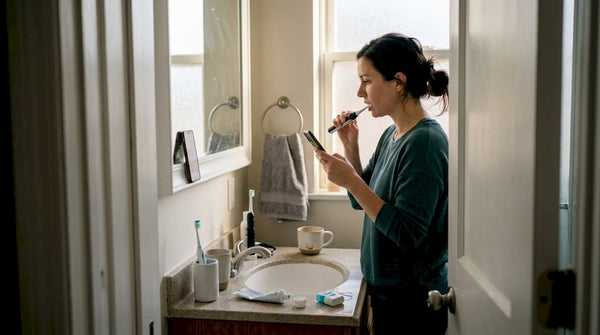 Woman brushing teeth in busy morning bathroom