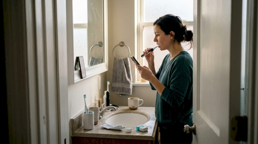Woman brushing teeth in busy morning bathroom