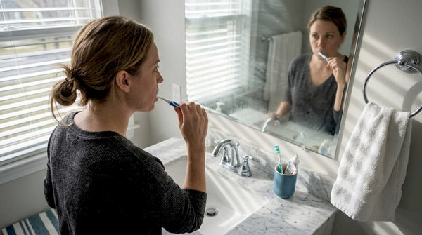 Woman brushing teeth at bathroom sink morning