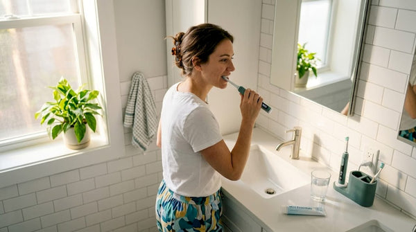 Adult brushing teeth with timer in bathroom