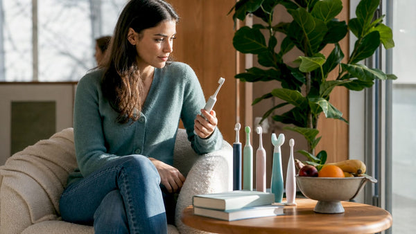 Woman comparing electric toothbrush alternatives in bathroom