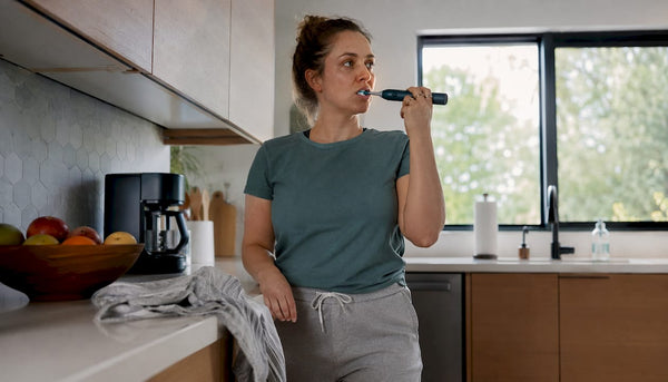 Woman brushing teeth with electric toothbrush