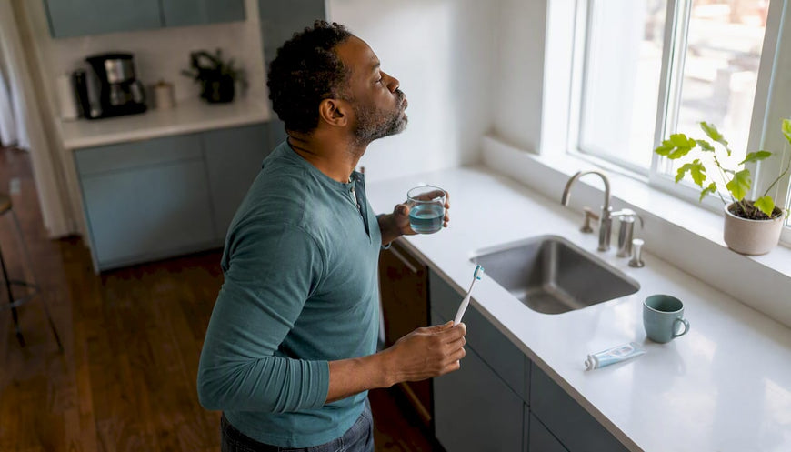 Man using mouthwash in bathroom mirror