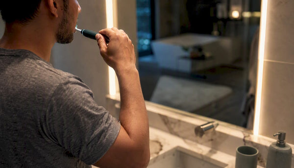 Close-up of hand brushing teeth with electric toothbrush