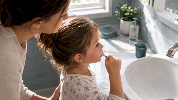 Parent supervising child brushing teeth