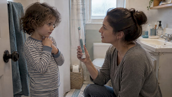 Parent calmly introducing electric toothbrush to child