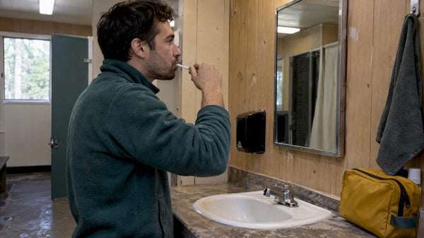 Adult dry-brushing teeth at a campground washroom