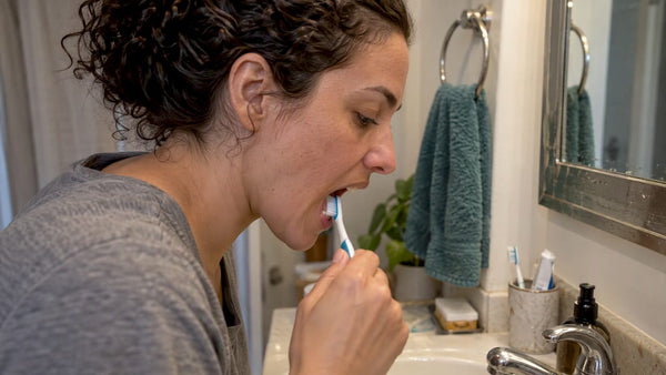 Woman brushing behind her lower front teeth