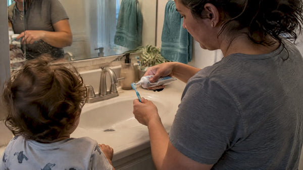 Parent measuring toothpaste for a toddler