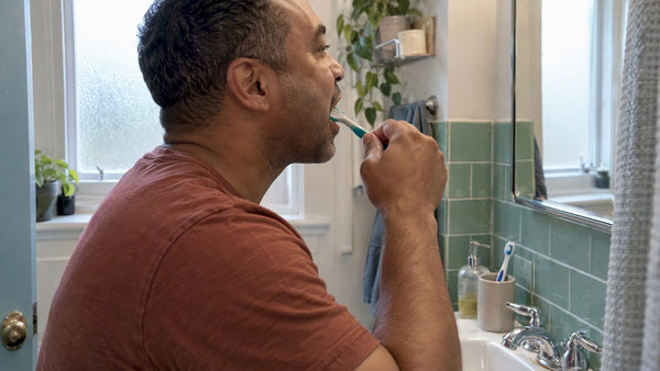 Adult brushing the back molars at a sink