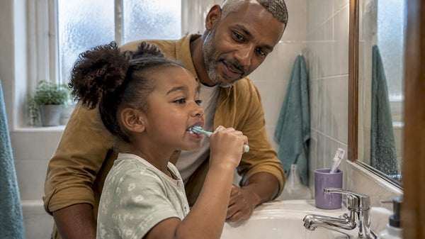 Parent helping child brush a loose baby tooth